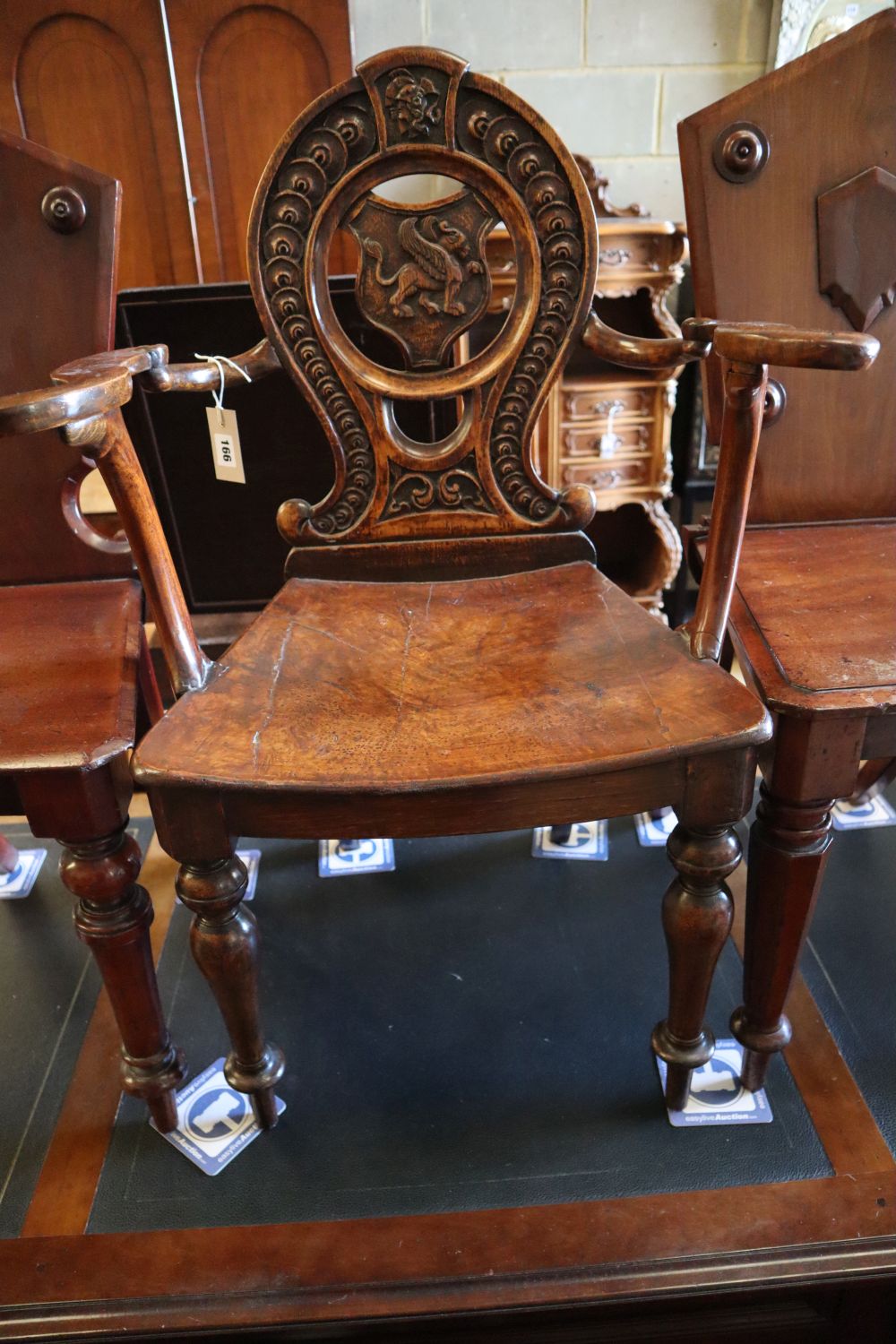 A 19th century carved oak hall elbow chair, together with two similar mahogany hall chairs